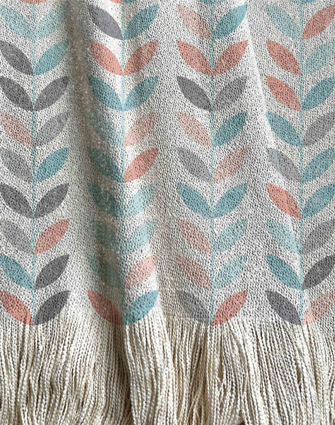 Manta tejida estilo enredadera, hojas de distintos colores en tonos aqua, gris y coral.